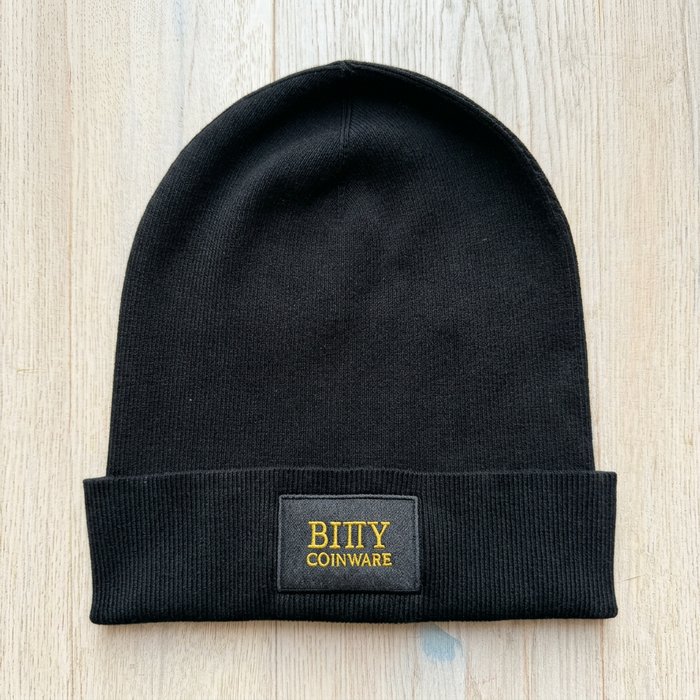 Schwarze Bitty Strickmütze mit Bitty-Coinware-Label auf dem Boden